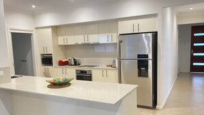 Una cocina moderna con armarios blancos, un refrigerador de acero inoxidable y una isla central con un tazón colorido.