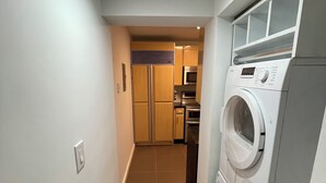 A laundry room with a front-loading washer and dryer, a microwave, and a refrigerator in the background. - Blocks Aways From Brickell Village, 2 beds 2 Baths FREE Parking NO Cleaning FEES (Miami)
