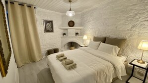 A bedroom with a large bed, a fireplace, a nightstand, and a lamp. - Leonys House by TrulyCyprus (Dhoros)