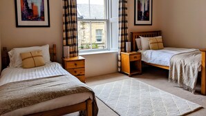 A bedroom with two beds, a window with curtains, and two framed pictures on the wall. - Huge 4 Bed Apt - Perfect Base to Explore The Borders (Jedburgh)