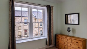 A room with a large window, a wooden dresser, and a mirror on the wall. - Huge 4 Bed Apt - Perfect Base to Explore The Borders (Jedburgh)