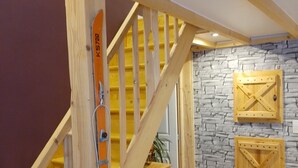 A wooden staircase with a handrail, a stone wall with wooden panels, and a small wooden cabinet. - Warm refuge for family vacations  (Saint-Jacques-des-Blats)