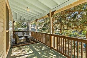 A covered porch with wooden railings, a cushioned seating area, and a view of a residential neighborhood. - Fullerwood Park Retreat 5 min to Downtown Sleeps 6 (St. Augustine)