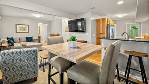 Une cuisine moderne avec une table en bois, des tabourets de bar et un four encastré.