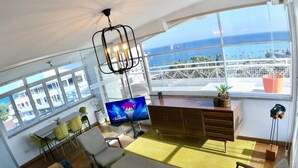 A modern living room with a large window, a TV, and a sofa. - 1-80 Collection Penthouse by TrulyCyprus (Limassol)