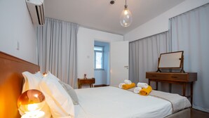 A hotel room with a bed, a bedside table with a lamp, a mirror, a dresser, and a window with curtains. - 1-80 Collection Penthouse by TrulyCyprus (Limassol)