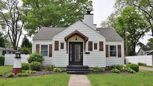 A single-story house with a black front door, white siding, and brown shutters.