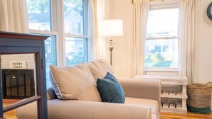 A cozy living room with a beige sofa, a lamp, and a fireplace.