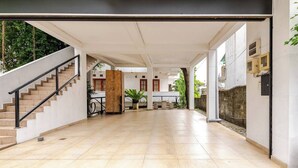 Un amplio espacio interior con una escalera, un pilar de madera y un suelo de baldosas.