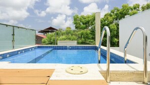 Una piscina al aire libre con una terraza de madera y barandales de metal.
