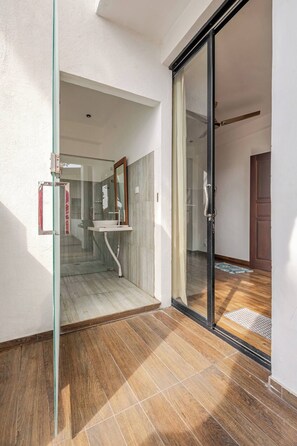 A modern bathroom with a glass shower enclosure, a sink, and a mirror.