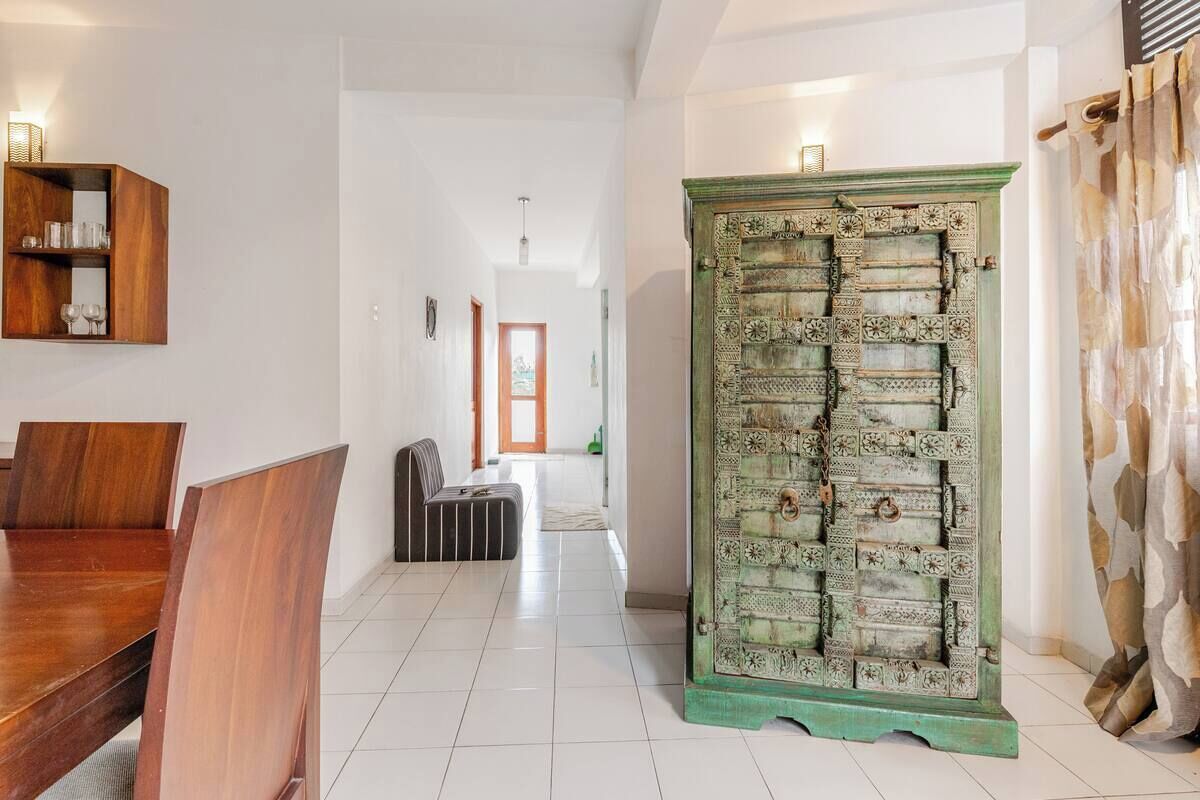 A spacious living area with a wooden dining table, a sofa, and a decorative green door.