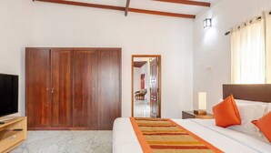 Habitación de hotel con una cama grande, televisión, armario y baño visible a través de una puerta abierta.