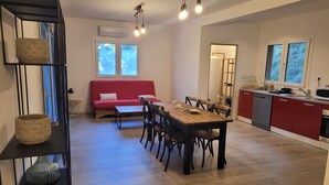 Una cucina moderna con zona pranzo, un divano rosso e un tavolo in legno.