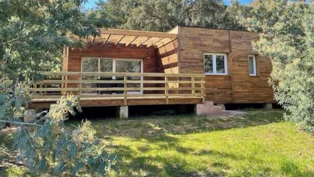Una baita di legno con veranda, circondata da alberi.