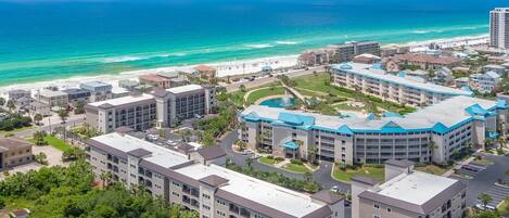 A coastal hotel with multiple buildings, a beach, and a clear view of the ocean.