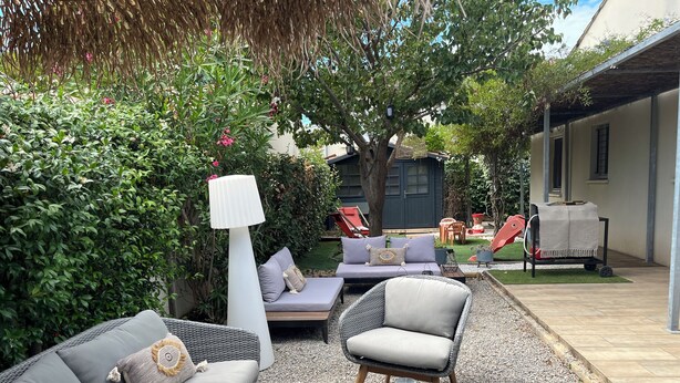An outdoor seating area with wicker furniture, a lamp, and a grill cart.