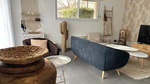 A modern living room with a blue sofa, a round coffee table, and a wooden side table with a woven basket.