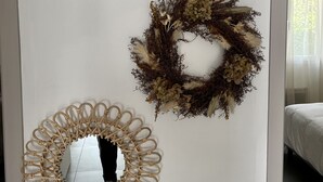 Three wall-mounted mirrors with circular frames, one with a floral wreath, and a bed in the background.