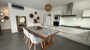 A modern kitchen with white cabinets, a wooden dining table, and white chairs.