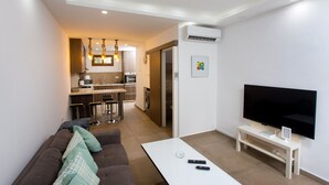 Een moderne woonkamer met een bank, een salontafel en een televisie op een dressoir.