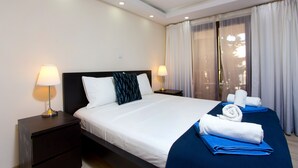 Een hotelkamer met een groot bed, twee nachtkastjes met lampen, een raam met gordijnen en uitzicht op de omgeving.