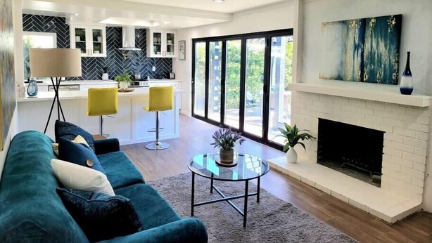 Een moderne woonkamer met een bank, een open haard en een keuken op de achtergrond.