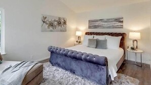 Een slaapkamer met een groot bed, twee nachtkastjes en kunstwerken aan de muur.