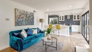 Een moderne woonkamer met een blauwgroene bank, een salontafel en een schilderij aan de muur.