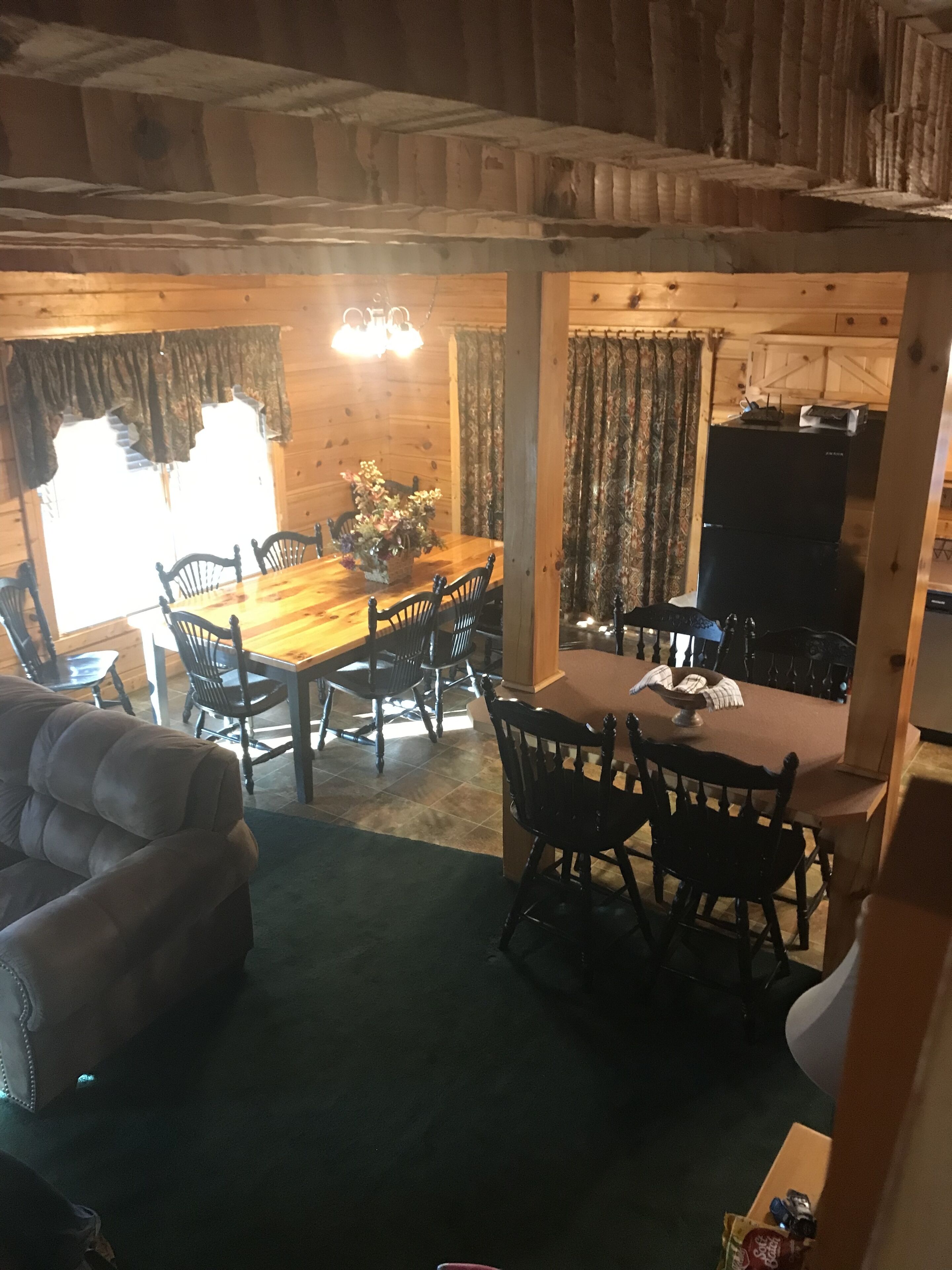 L’intérieur d’un chalet chaleureux, avec une table à manger en bois, des chaises et un canapé.