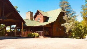 Een lodge met een overdekte veranda, schoorsteen en een lange oprit.