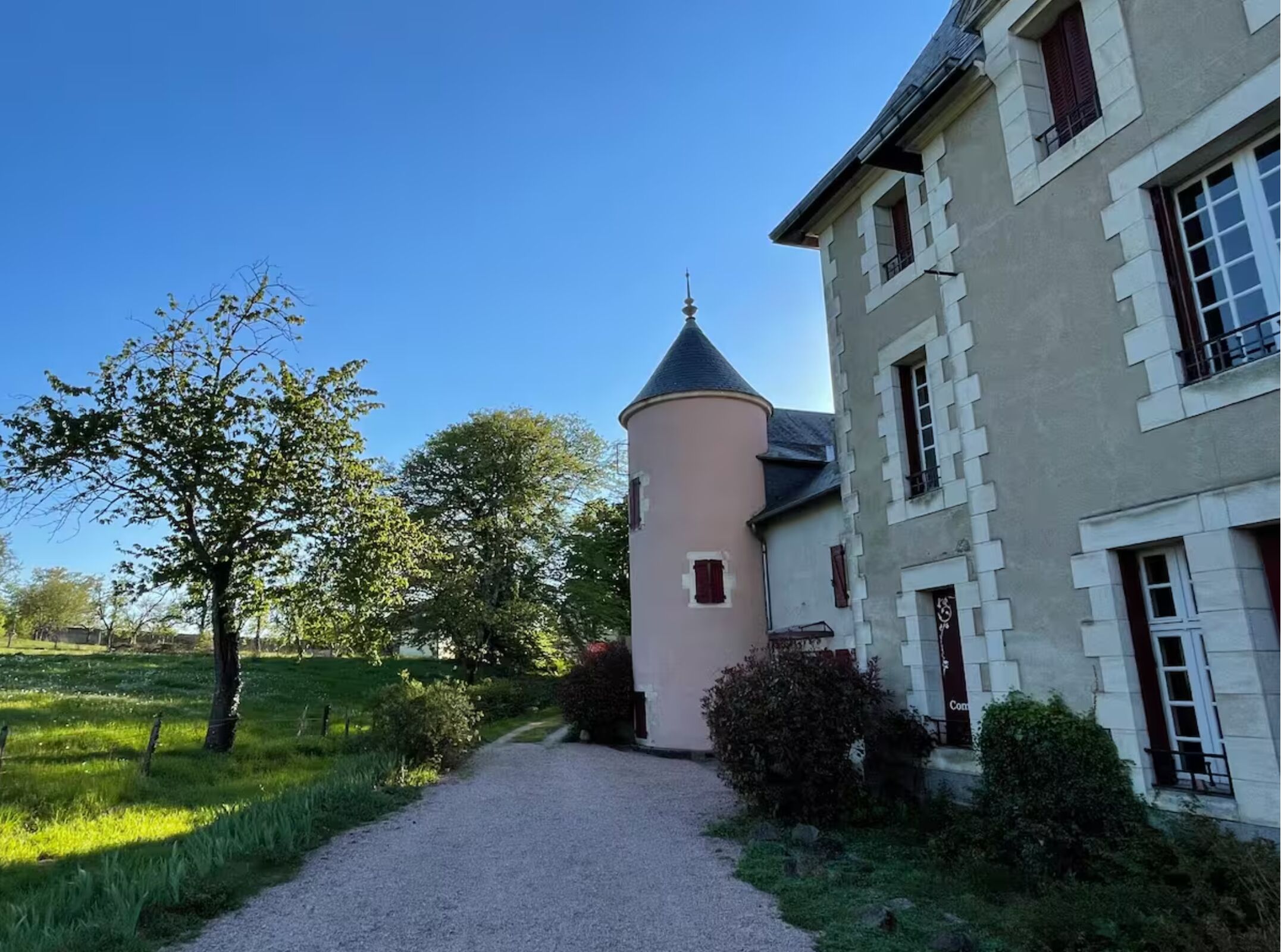 A building with a tower, a paved path, and greenery.