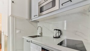 A modern kitchen with a built-in washing machine, a coffee maker, and a microwave.