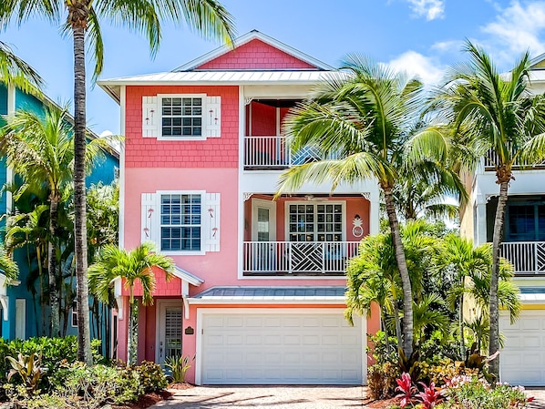 A two-story house with a red and white facade, a balcony on the second floor, and a garage. - Luxury Key West feel steps from Historic downtown Stuart, minutes from the beach (Stuart)