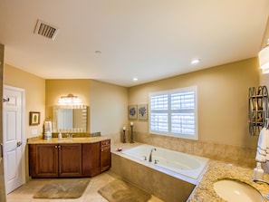 A bathroom with a large bathtub, a vanity with a mirror, and a window with blinds. - Luxury Key West feel steps from Historic downtown Stuart, minutes from the beach (Stuart)