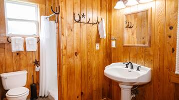 A wooden-paneled bathroom with a toilet, sink, and towel rack.