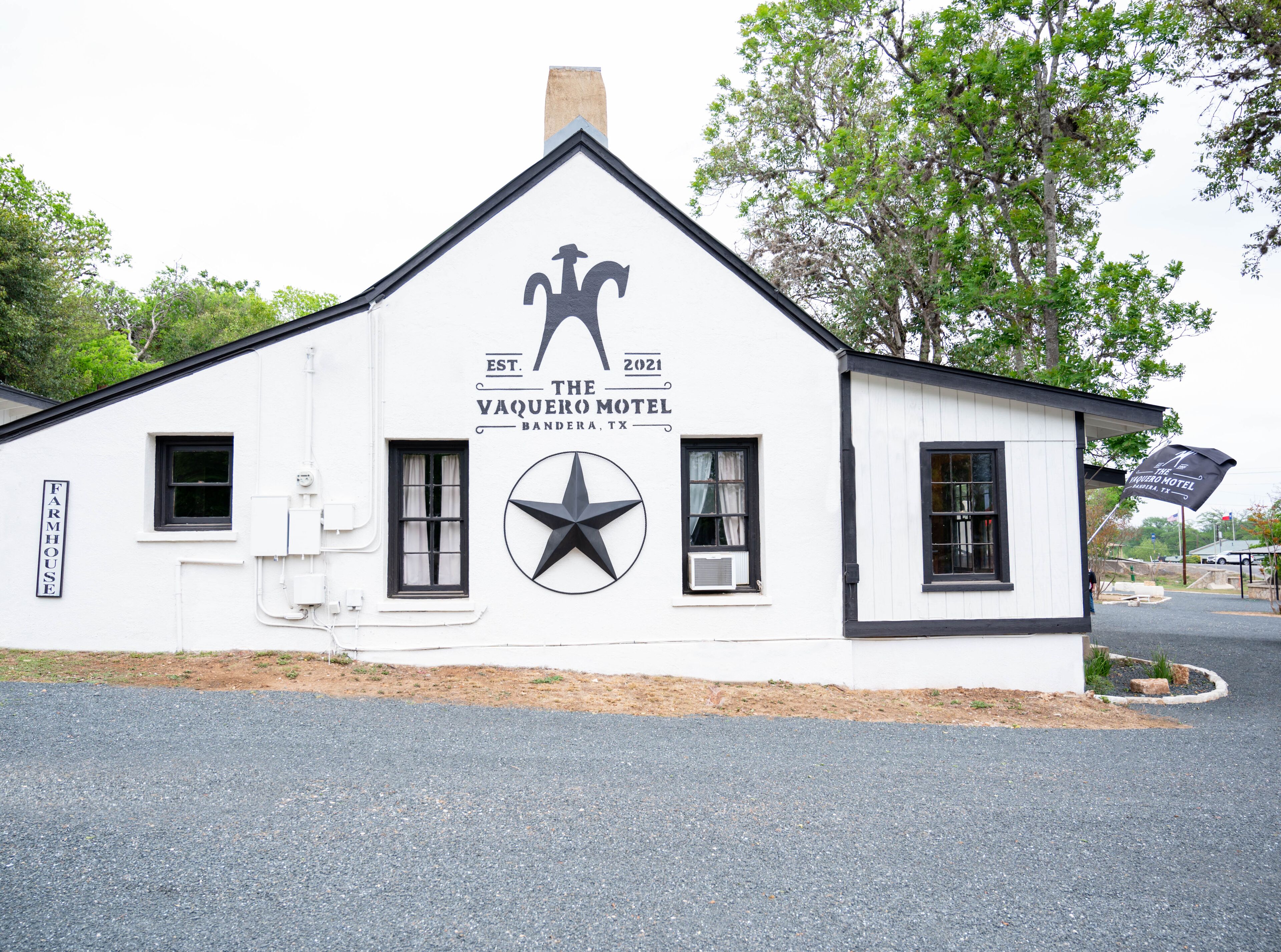 A white building with a black roof, a star logo, and a sign that reads "The Yaquero Motel Bandera, TX".