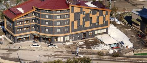 A multi-story hotel with a distinctive architectural design, featuring a combination of dark and light materials, and a red roof.