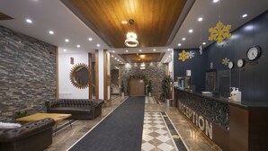 A hotel reception area with a check-in counter, a reception desk, a waiting area with a sofa and a coffee table, and a hallway leading to the elevators. - Balsoy Mountain (Erzurum)