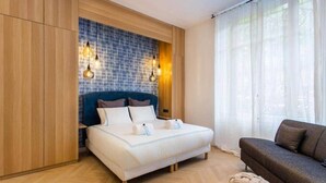 Une chambre à coucher avec un lit, un canapé et un mur orné d’un motif de carreaux bleus.