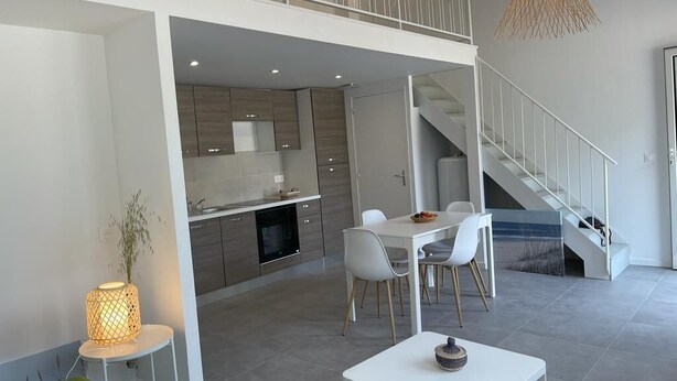 Ein modernes Interieur mit Essbereich, Küche und Treppe.