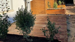 Ein weißes Gebäude mit rotem Ziegeldach, einem Holztor und einer Holzterrasse, die zu einer Tür führt.