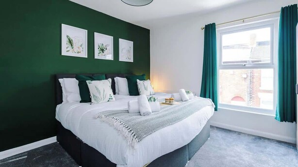 A bedroom with a bed, green walls, and a window with curtains. - Fresh house, amazing location, great for couples! (Chester)