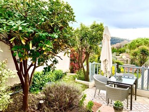 Una terrazza esterna con tavolo e sedie, immersa nel verde e con vista sulla campagna.