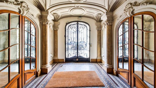 A grand hallway with ornate columns, a large arched doorway, and a patterned carpet. - #Arc DeTriomphe #Trocadero #Style Haussmanien#AC (Paris)