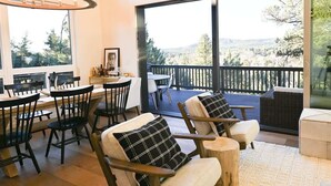 A dining area with a table and chairs, a chandelier, and a view of the outdoors.