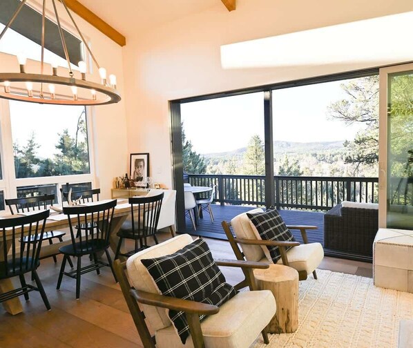 A dining area with a table and chairs, a chandelier, and a view of the outdoors. - OutWest Wapiti Rim Cabin (Pine)