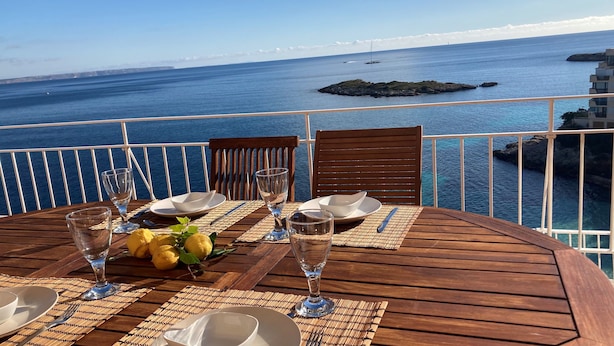 A table set for two with a view of the sea and rocky outcrops.