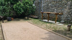 A square outdoor area with a wooden bench and a stone wall in the background.