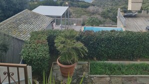 A coastal view with a clear sky, a swimming pool, and a garden area.